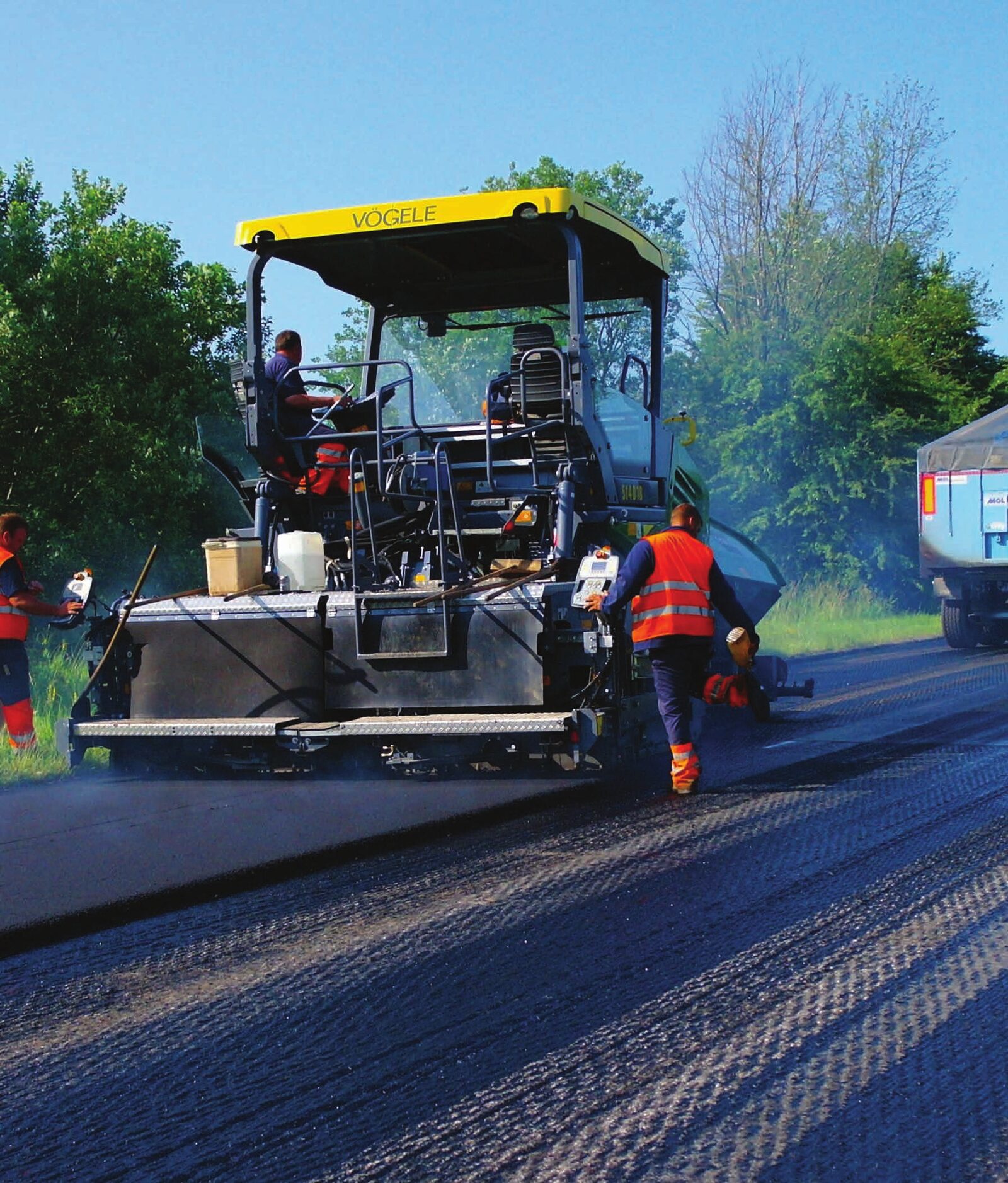 Paving crew laying fresh asphalt on a rural road